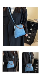 Detail view of denim crossbody bag with vintage wooden handle and metal kiss-lock closure
