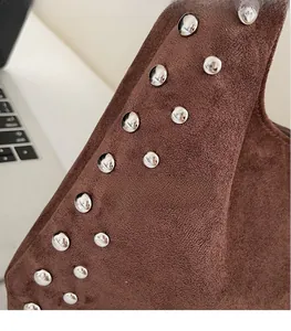 Close-up of brown suede shoulder bag with decorative silver metal rivets on the side