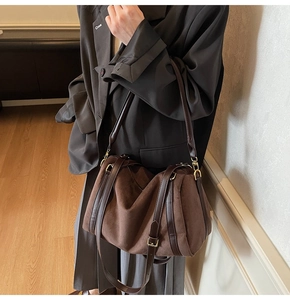 Détail du sac Boston en daim marron avec sangles en cuir et ferrures dorées