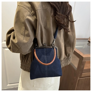 Detail of vintage denim doctor bag with brown round handle and metal frame closure
