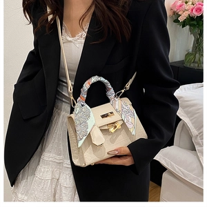 Detailed view of crocodile texture bag with gold twist lock and printed silk scarf handle