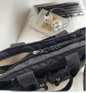 Detail view of black quilted tote bag with smooth metal zippers and multiple pockets