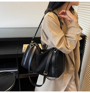 Détail du sac bandoulière en daim noir avec boucles dorées et lanières en cuir