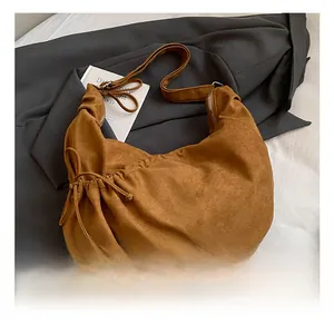 Detail of caramel brown suede hobo bag with side drawstring and wide shoulder strap