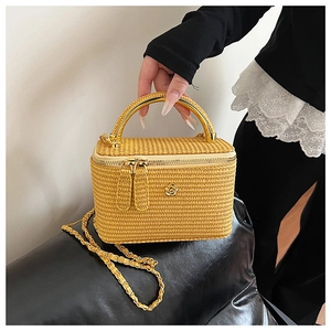 Detail of yellow woven vanity case bag with gold metal handle and camellia logo detail