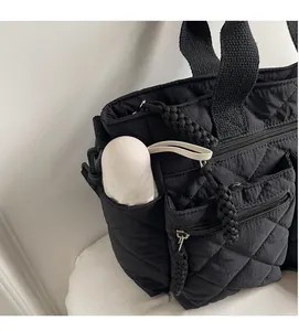 Detail view of black quilted shoulder bag featuring side pockets for water bottle storage