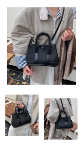 Detail of black canvas and leather tote bag featuring double handles and detachable strap