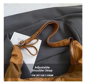 Detail showing the adjustable shoulder strap and silver metal buckle on the brown suede bag