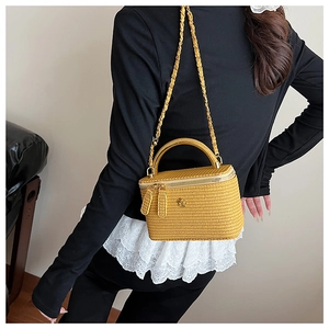 Detail of yellow woven box bag showing gold hardware and textured fabric material