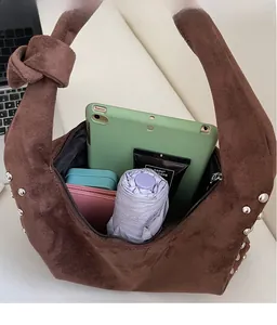 Macro detail of large brown suede tote bag with silver rivets and spacious inner storage
