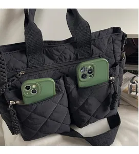 Detail of black quilted tote bag showing two functional front zipper pockets for storage