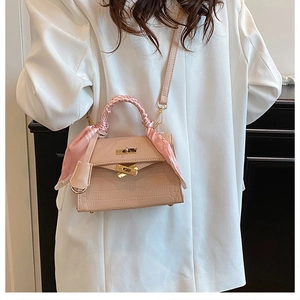 Close-up of pink croc-embossed leather handbag with silk scarf wrapped handle detail