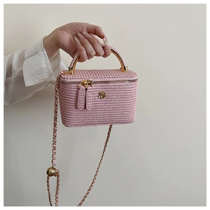 Detail of pink woven mini box bag with golden metal handle and camellia ornament
