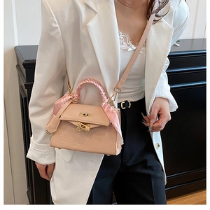 Detail of pink croc-embossed bag with gold lock and decorative silk scarf handle