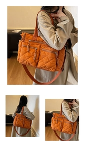 Detail of an orange quilted tote bag with multiple zipper pockets and woven pullers