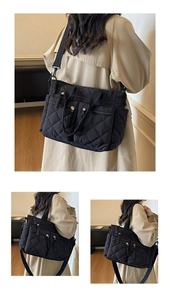 Detail of black quilted tote bag showing multiple zipper pockets and wide shoulder strap