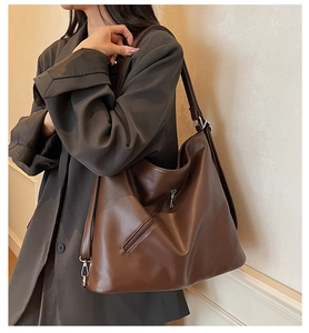 Detailed view of dark brown leather tote with silver metal zipper and clasp hardware
