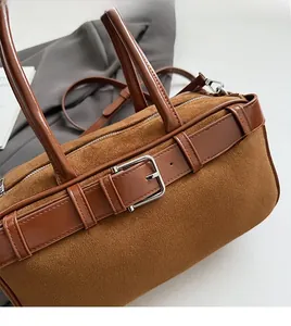 Detail of caramel suede tote bag featuring adjustable metal buckles and soft texture