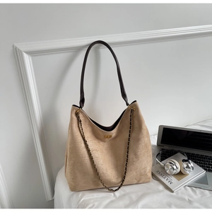 Detail of apricot suede tote bag with brown shoulder strap and decorative gold chain