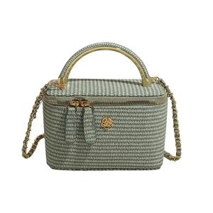 Minimalist green woven mini box bag with golden metal handle and floral emblem accent