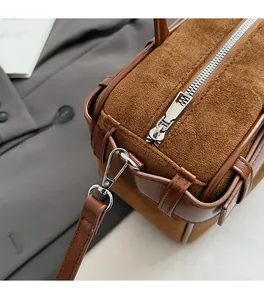 Detail of silver-tone metal hardware and suede patchwork on a brown bucket bag