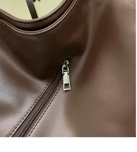 Detailed macro view of a smooth silver square zipper slider on a vintage brown leather bag