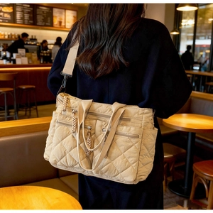 Detail view of beige quilted tote bag with multi-pocket design and adjustable shoulder strap