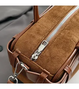 Detailed close-up of smooth silver zipper and metal buckle on brown suede bucket bag