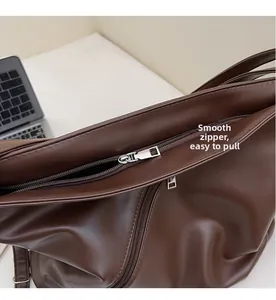 Detail of smooth metal zipper closure on the dark brown PU leather tote bag surface