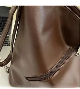 Close-up of vintage dark brown leather backpack showing side zipper and refined texture