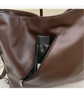 Detail of dark brown leather tote showing exterior zipper pocket with ample storage space