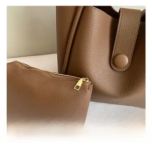 Close-up of brown lychee texture leather tote bag with golden zipper and leather buckle