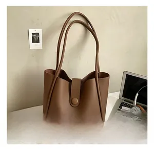 Brown lychee texture tote bag on a desk with a laptop, headphones and magazines