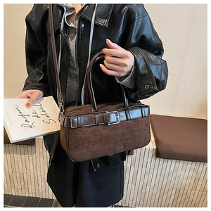 Detailed view of dark brown suede patchwork bucket bag with metal buckle strap and handle