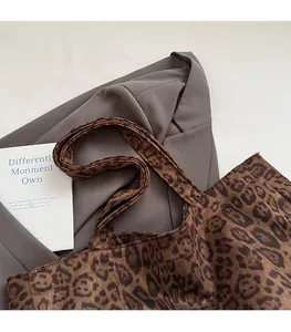 Close-up of leopard print tote bag with wide strap on a grey blazer background