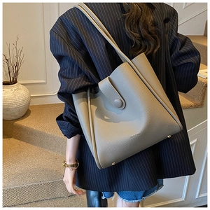 Close-up of gray lychee leather tote bag with magnetic closure and metal studs