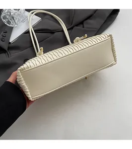 Detail des flachen Taschenbodens und der feinen Falten einer cremeweißen Tasche
