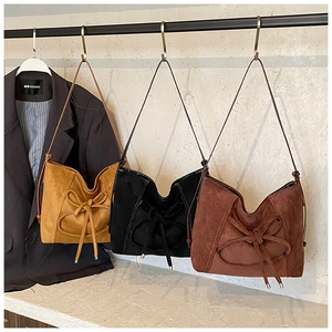 Three retro matte suede tote bags in yellow, black, and brown with bow details hanging