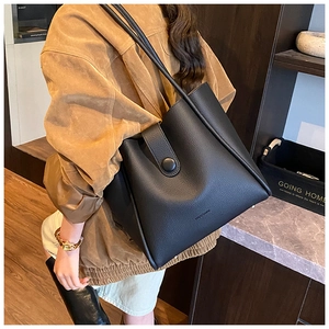 Close-up of black pebble grain leather tote bag featuring brand logo and shoulder strap detail