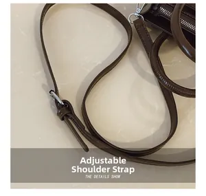 Detail of dark brown leather handbag showing adjustable strap and silver metal hooks