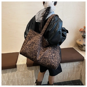 Detail view of large leopard print tote bag on shoulder showing canvas texture and size