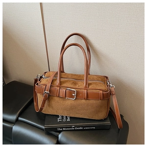 Detailed view of brown suede bucket bag texture with smooth leather straps and silver hardware