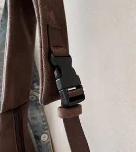Detalle de correa ajustable y hebilla de plástico en bolso de gamuza sintética marrón