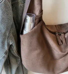 Detalle del bolso tote de ante marrón con un bolsillo lateral y una correa ancha