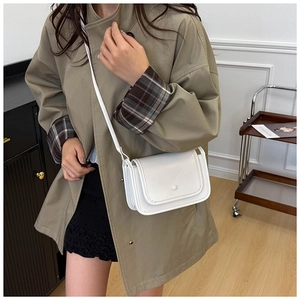 Piccola borsa a tracolla bianca in pelle indossata da una modella per uno stile casual chic