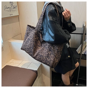 Macro detail of high-capacity leopard print tote bag with thick canvas texture on shoulder