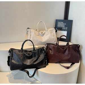 Detailed view of woven texture and handle on large travel bags in black and brown