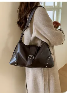 Modella che indossa una borsa tote in pelle marrone opaca con borchie e chiusura a fibbia