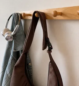 Detalle de la correa ajustable con hebilla negra en el bolso tote de ante marrón
