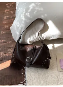 Dettaglio della borsa tote in pelle marrone scuro con borchie argentate e fibbia vintage